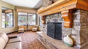 A room with a stone fireplace, a sofa, a chair, and a table.