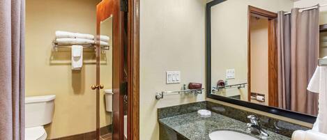 A bathroom with a toilet, a sink, a mirror, and a towel rack.