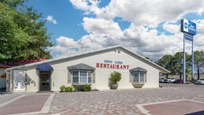 A building labeled 'Alpine Lodge Restaurant' with a paved entrance and a clear sky with clouds. - Best Western Swiss Clock Inn (Pecos)