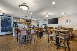 A bar area with wooden furniture, a chalkboard menu, and a television. - Best Western Swiss Clock Inn (Pecos)