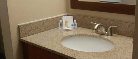 A bathroom with a sink, mirror, towel rack, and a shelf with towels.