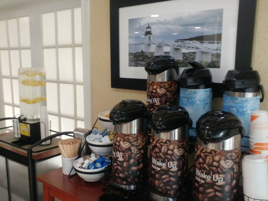 A coffee station with multiple coffee makers and disposable cups.