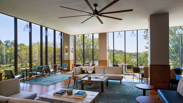 A spacious living area with a large window, a ceiling fan, and a variety of seating options. - Merriweather Lakehouse, Autograph Collection (Columbia)