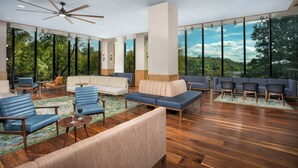 A spacious indoor area with multiple seating options, a ceiling fan, and large windows offering a view of the outdoors. - Merriweather Lakehouse, Autograph Collection (Columbia)