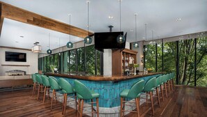 A modern bar area with a pool table, bar stools, and a television screen. - Merriweather Lakehouse, Autograph Collection (Columbia)