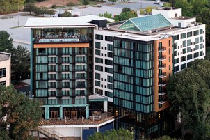 A modern hotel with multiple floors, large windows, and a rooftop terrace.