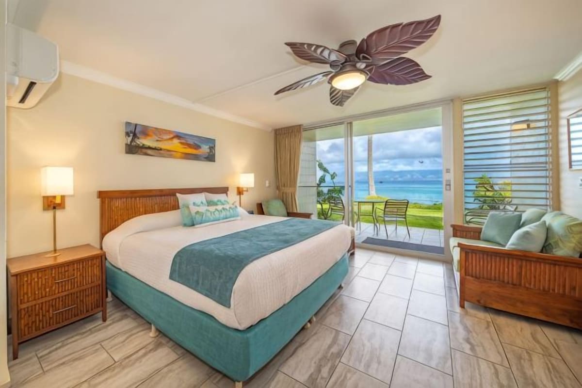 Quarto com cama, mesas de cabeceira, ventoinha no teto e varanda com vista.