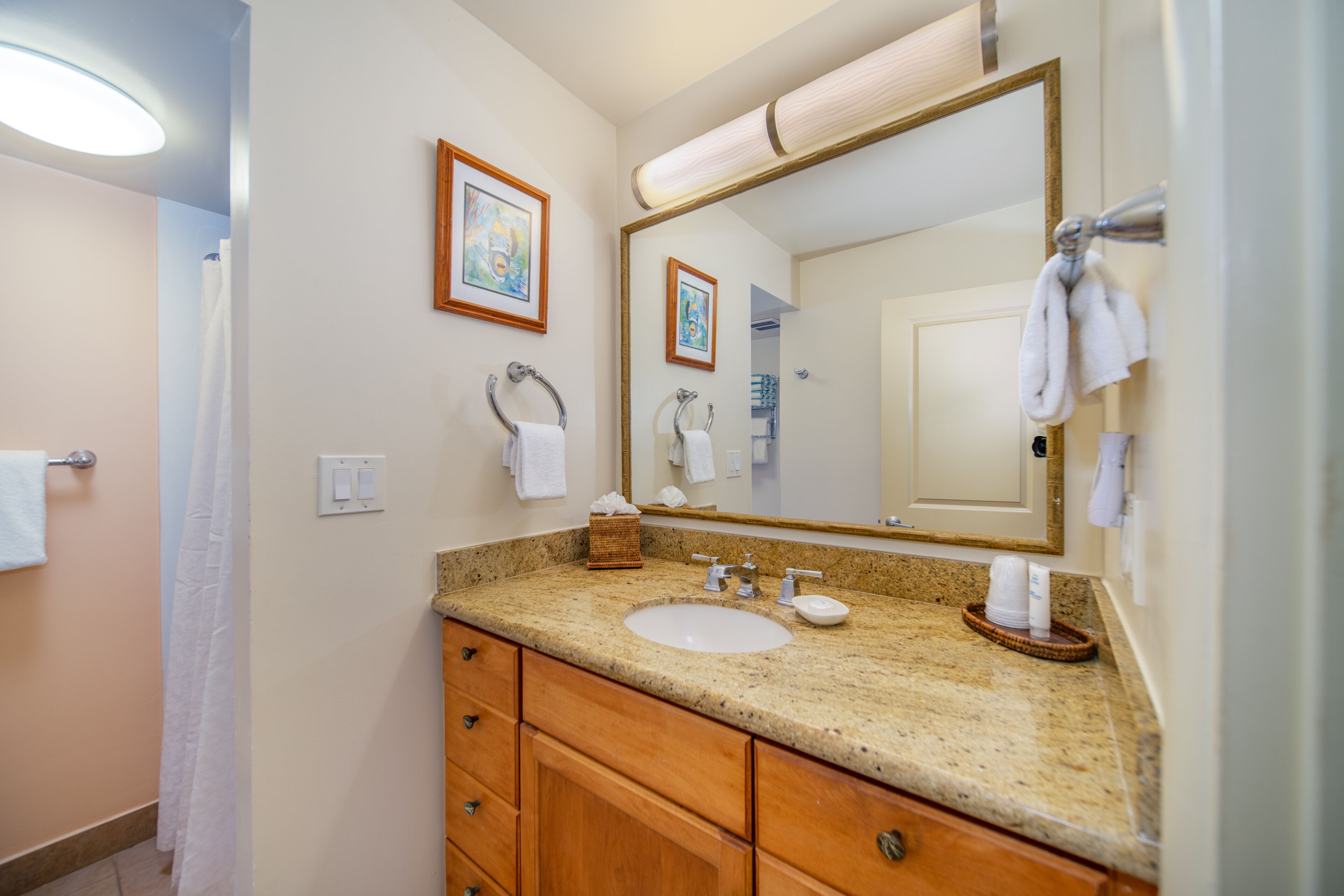 Une salle de bain avec un lavabo à vasque en granit, un meuble-lavabo en bois et un grand miroir.