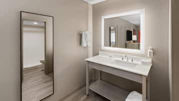 Un baño moderno con un espejo grande, dos lavamanos y un perchero para toallas.