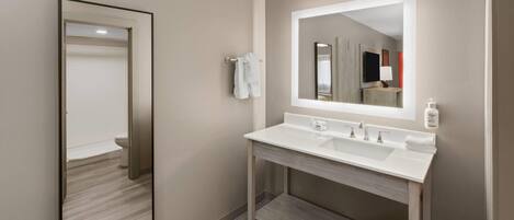 Un baño moderno con un espejo grande, dos lavamanos y un perchero para toallas.