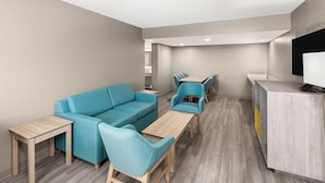 Eine moderne, neutral gestaltete Lounge mit einer Couch, Sesseln, einem Holztisch und einer Rezeption.