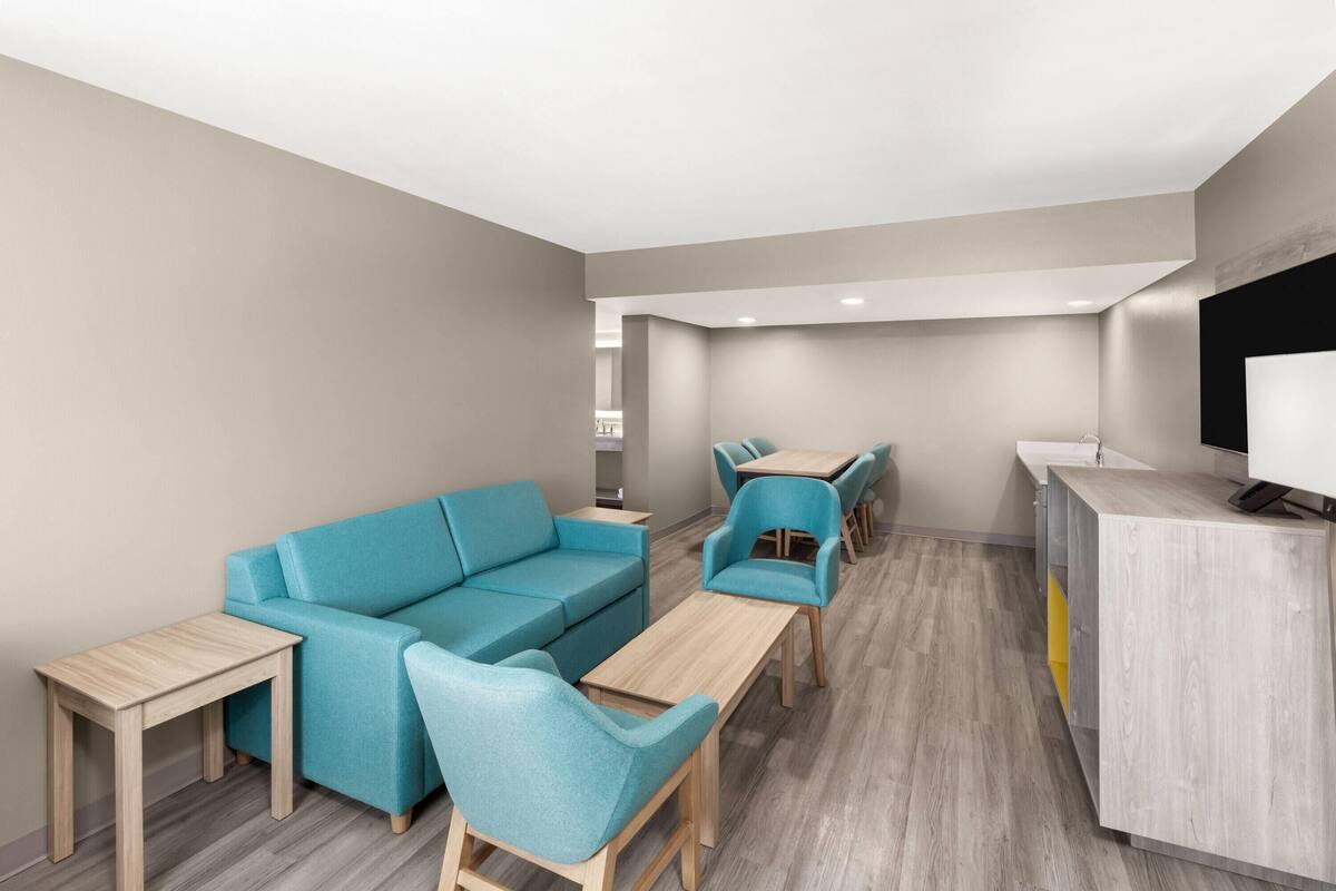 A modern, neutral-colored lounge area with a sofa, chairs, a wooden table, and a reception desk.
