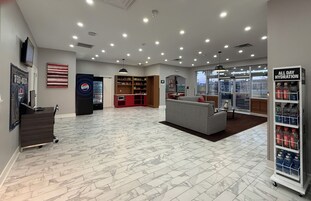 Um hall amplo com área de estar, máquina de vendas automática e refrigerador de Pepsi.