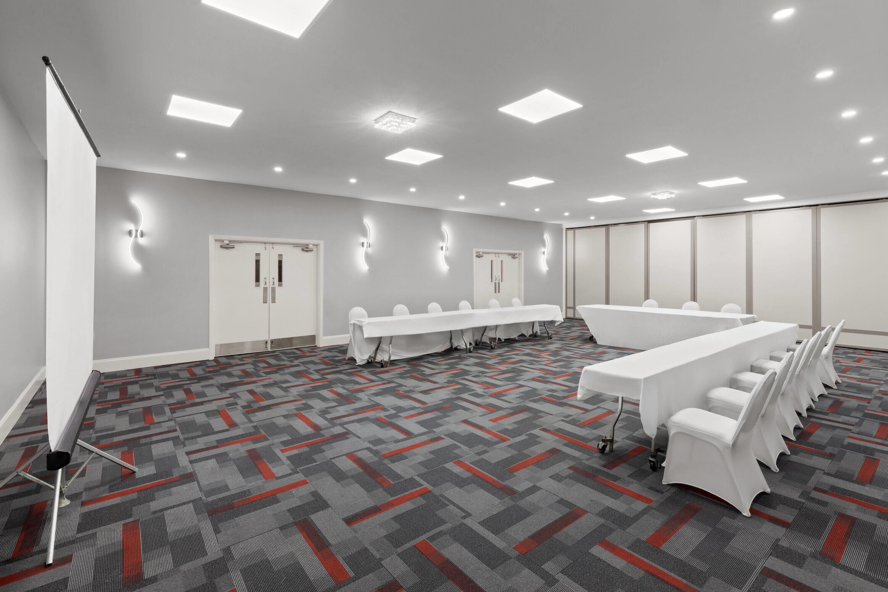 A conference room with a long table, chairs, and a projector screen.