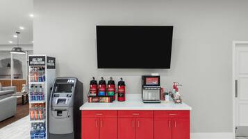 Habitación de hotel con minibar, televisión de pantalla plana, cafetera y dispensador de agua.