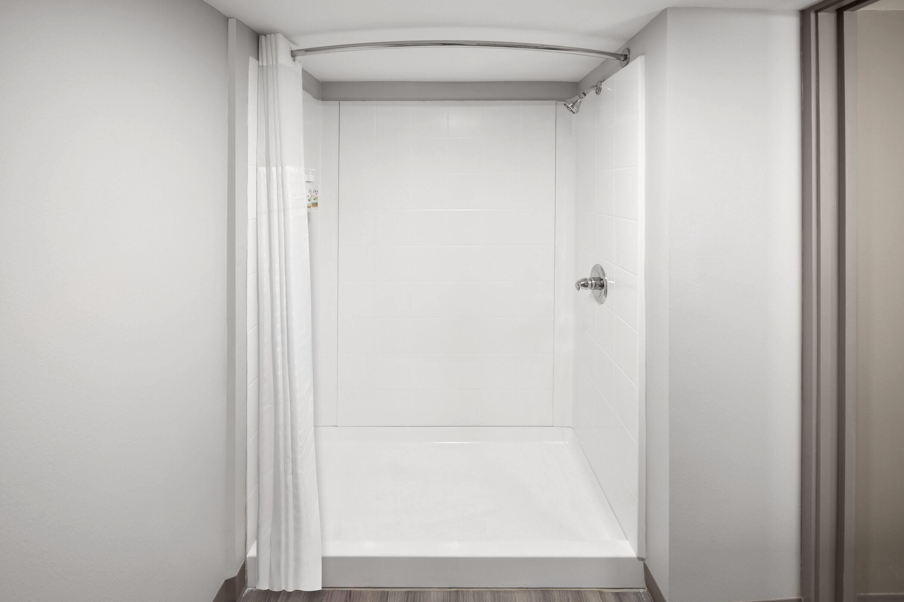 Een moderne, lege badkamer met witte wanden en een douchegedeelte.