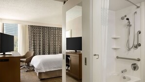 A hotel room with a bed, desk, TV, and a shower area. - Hampton Inn Atlanta Buckhead (Atlanta)