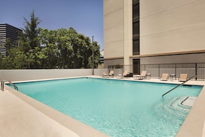 A rectangular pool with clear blue water, surrounded by a beige deck. There are lounge chairs along the pool's edge.