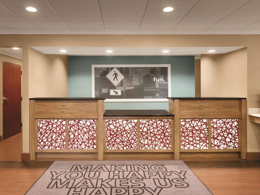 A reception area with a wooden desk, a red geometric patterned partition, and a welcome mat.