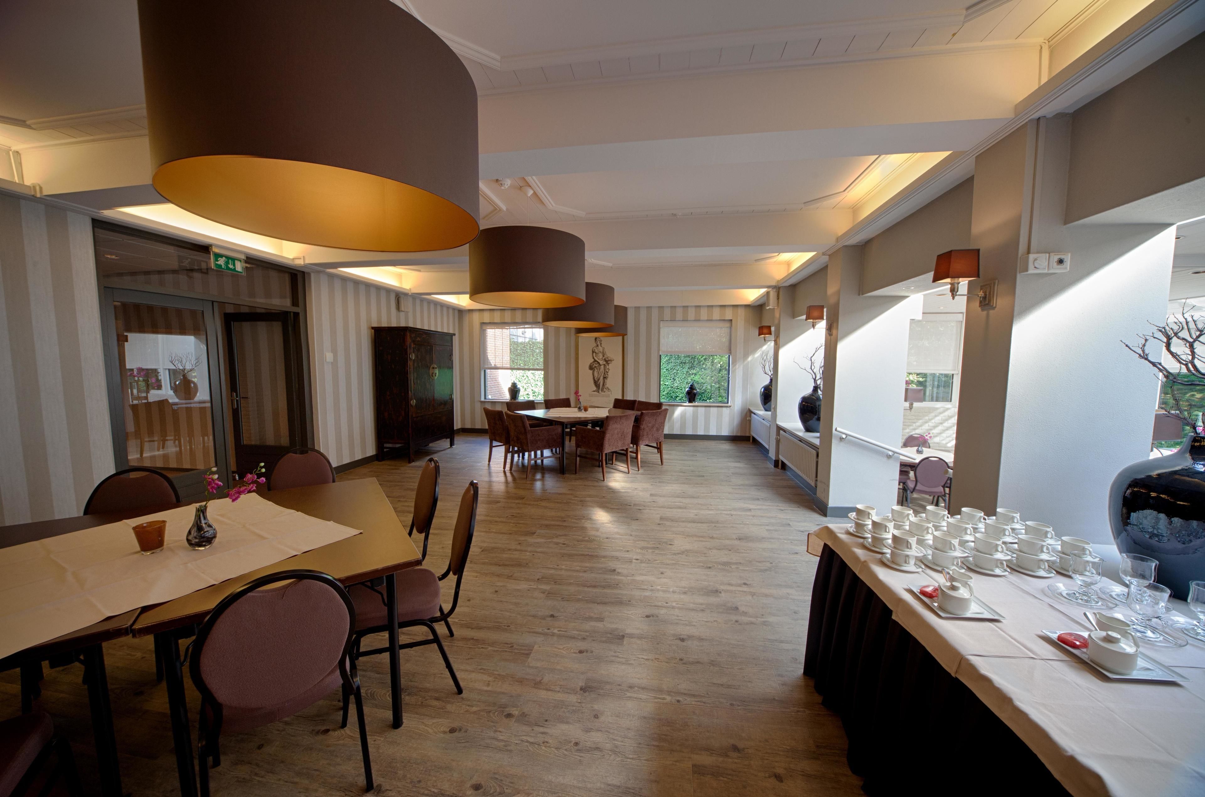 A spacious dining area with a long table set for a meal, surrounded by chairs.