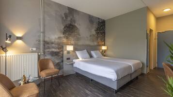 Una habitación de hotel moderna con una cama grande, dos lámparas de noche, un radiador, una silla y una pared con un mural texturizado.