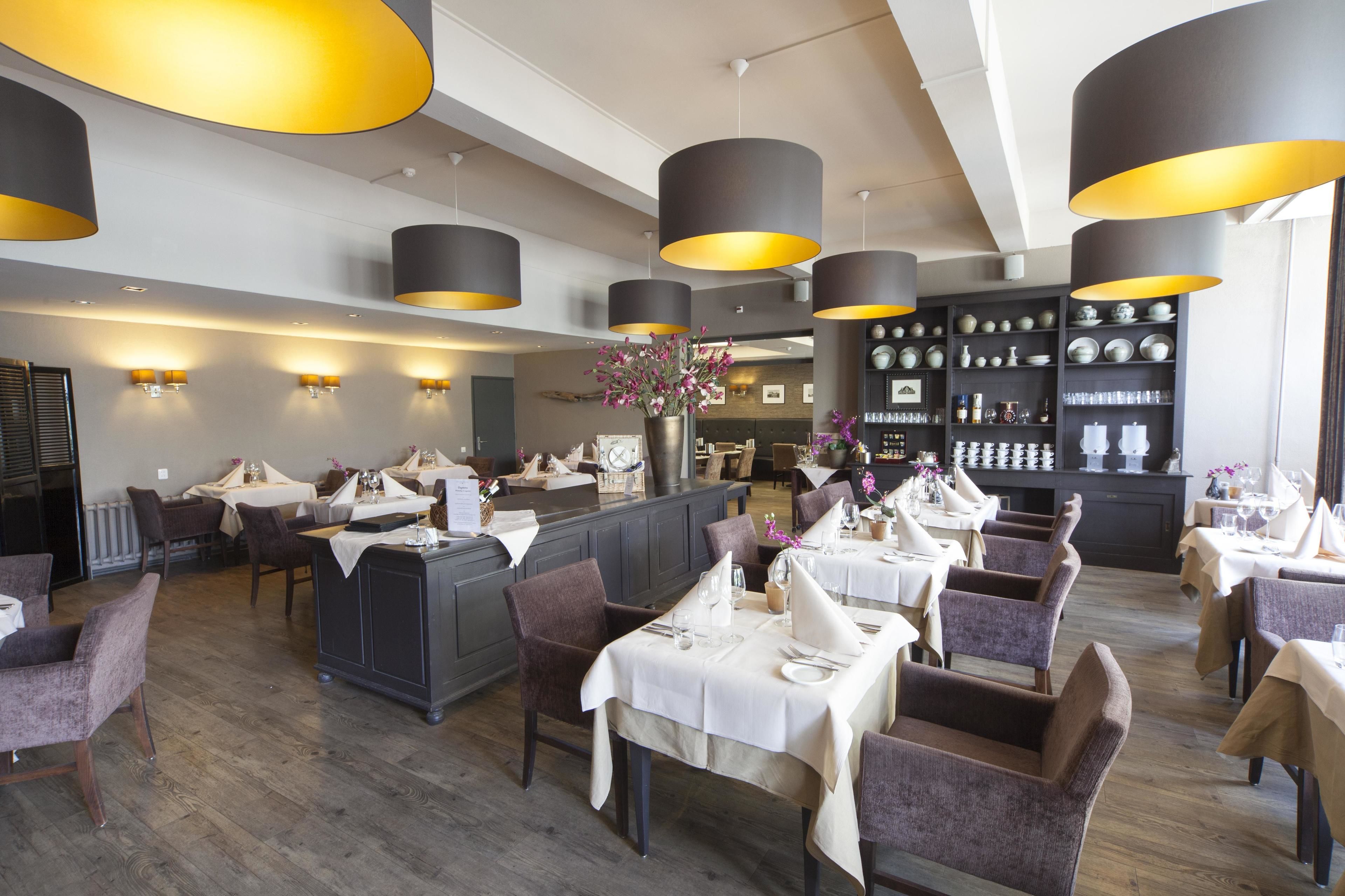 Un restaurante con varias mesas, sillas y una zona de bar.