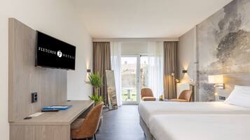 A hotel room with a bed, a desk, a chair, a television, and a view of the outdoors.