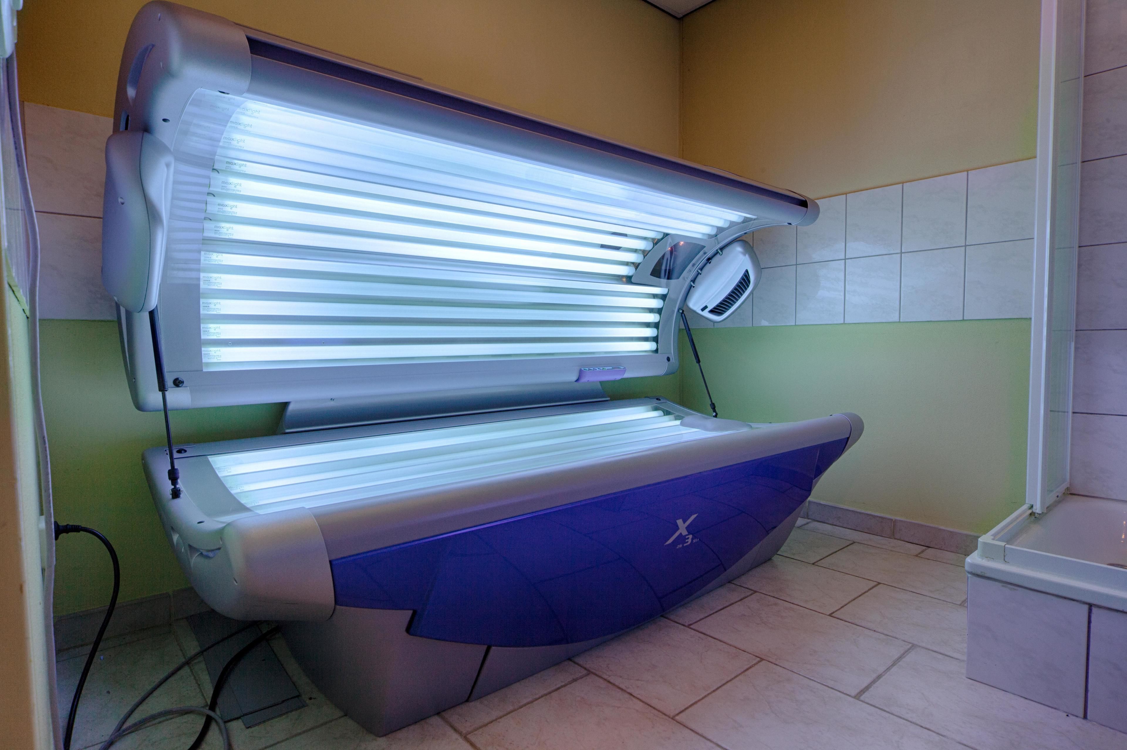 A tanning bed with a control panel and a footrest.