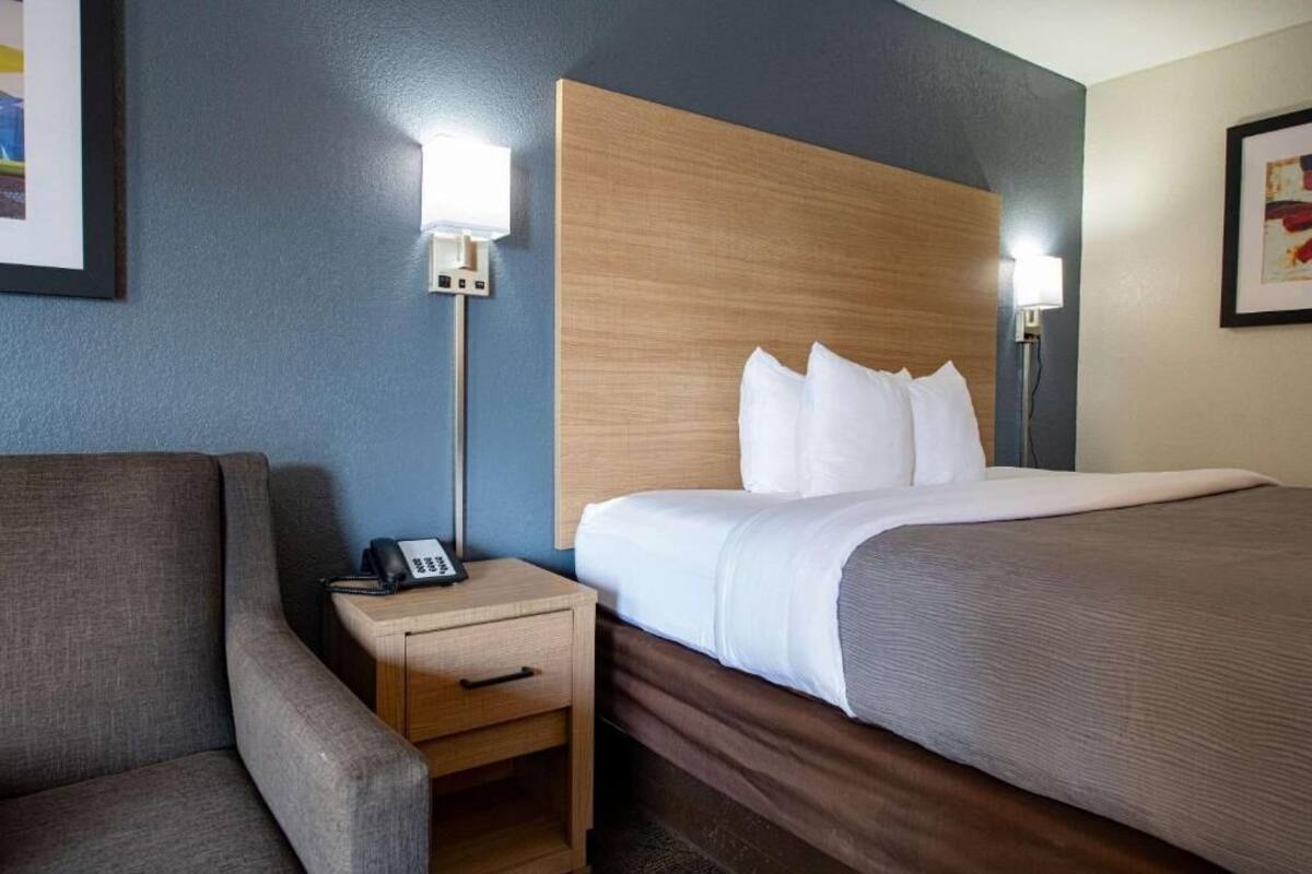 Ett hotellrum med en säng, en sänglampa, ett nattduksbord och en stol.