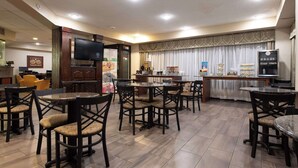 A restaurant with multiple tables and chairs, a television, and a counter with food displays.
