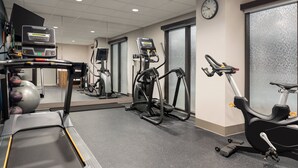 Een sportschool met loopbanden, elliptische trainers en een hometrainer.