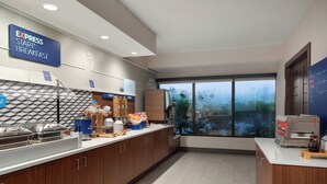 Een moderne keuken met een ontbijtbalk, een buffetopstelling en een groot raam met uitzicht op de omgeving.