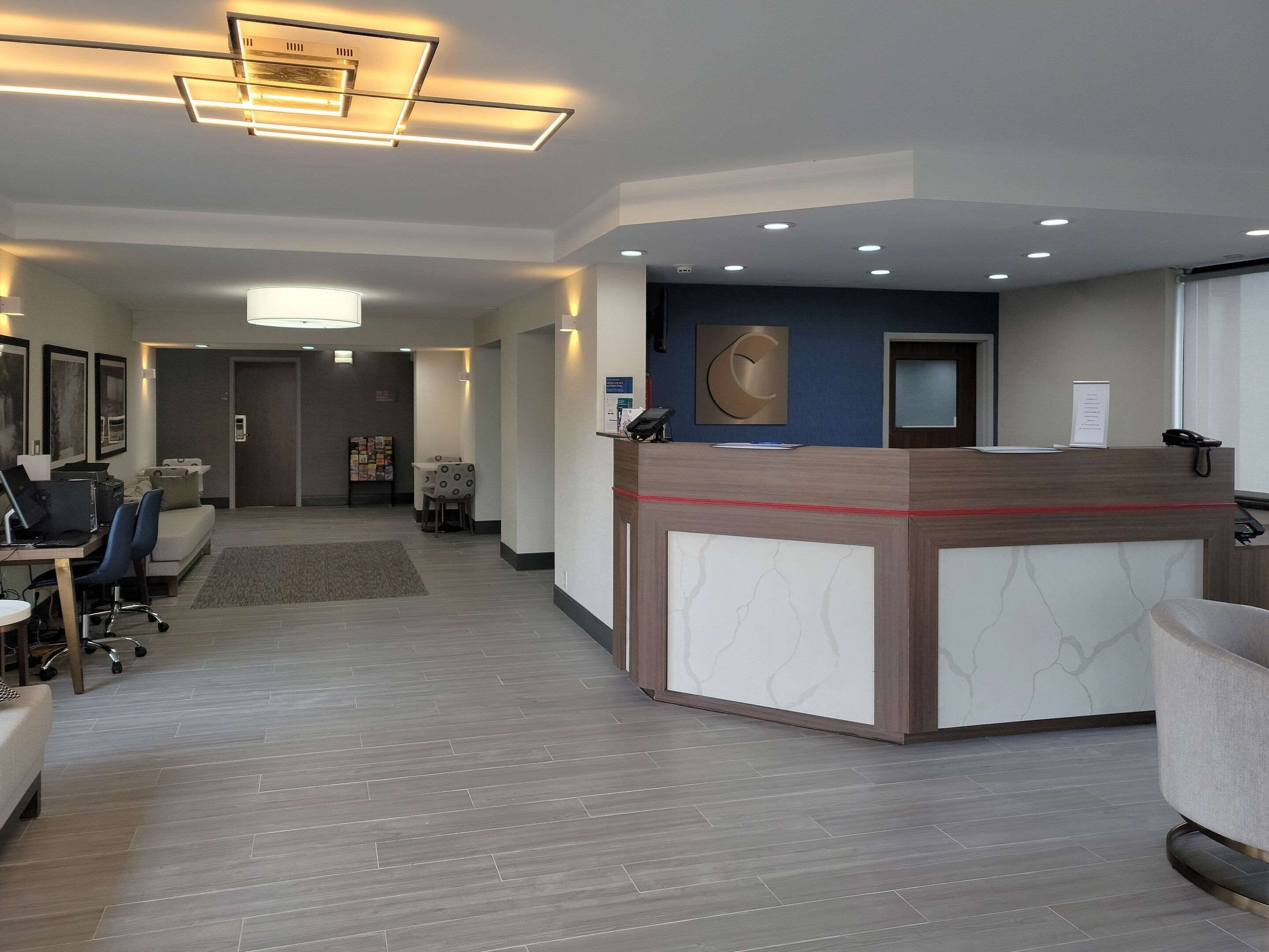 A hotel reception area with a modern design, featuring a reception desk, seating area, and a hallway leading to guest rooms.