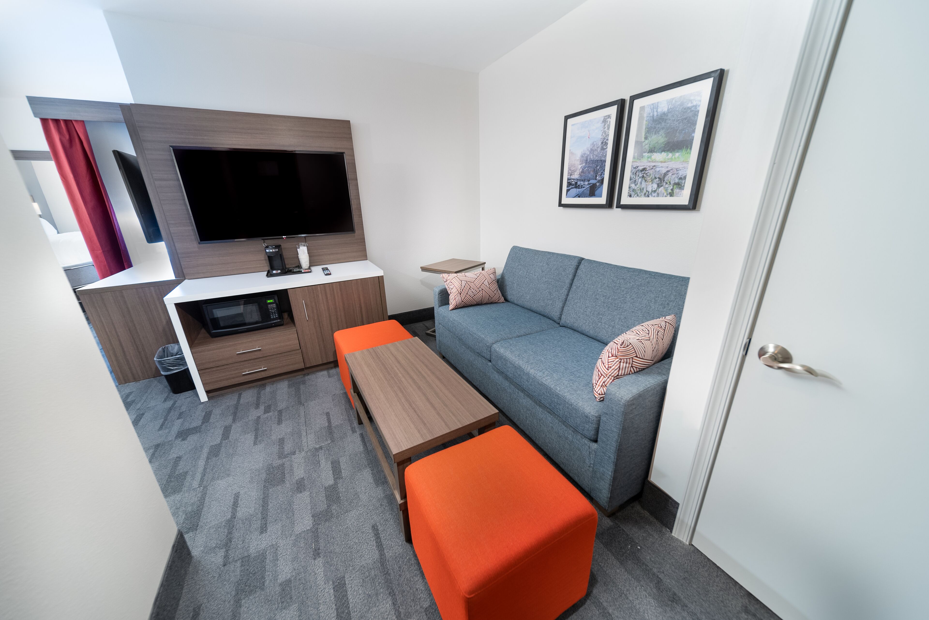 A compact living space with a sofa, ottoman, coffee table, TV, and kitchenette.
