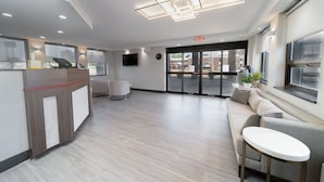 A modern reception area with a reception desk, seating area, and large windows.