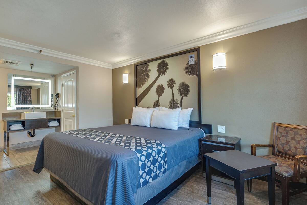 Ein Hotelzimmer mit einem großen Bett, einem Schreibtisch, einem Stuhl, einem Spiegel und einer Wandleuchte.