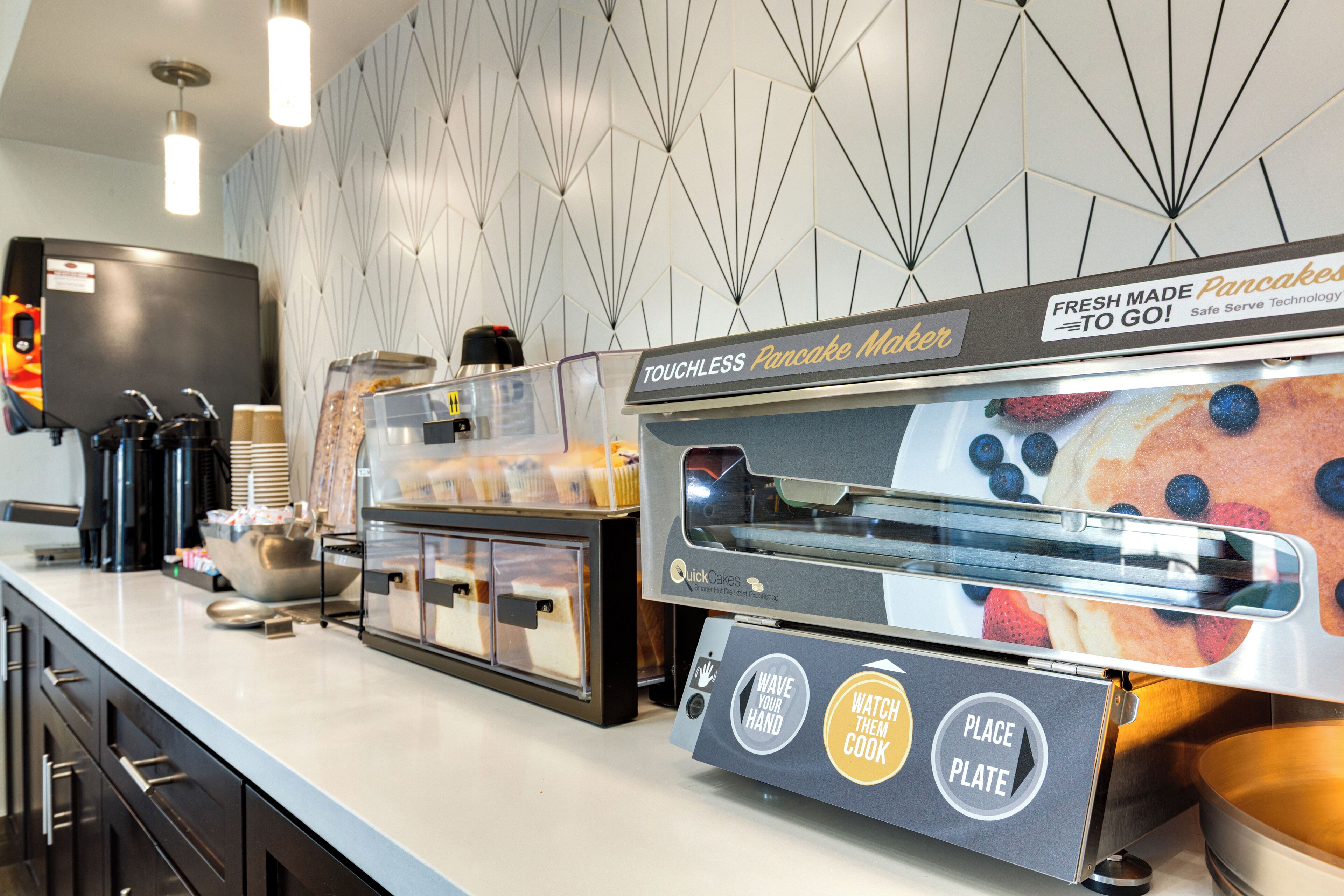 A touchless pancake maker and coffee machine in a modern kitchen area.