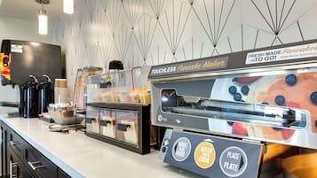 A touchless pancake maker and coffee machine in a modern kitchen area.