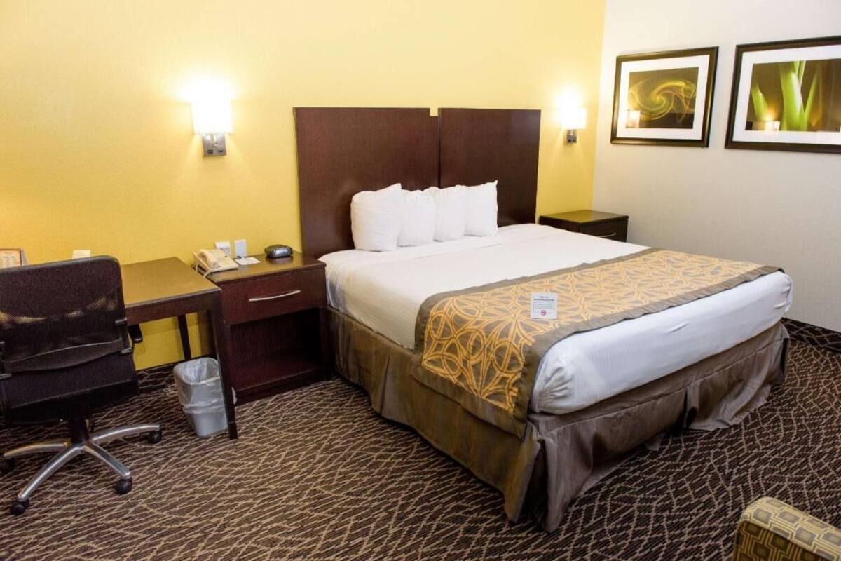 A hotel room with a bed, desk, chair, and two wall-mounted lamps.