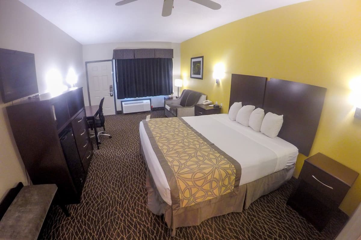A hotel room with a bed, desk, chair, and a small table.