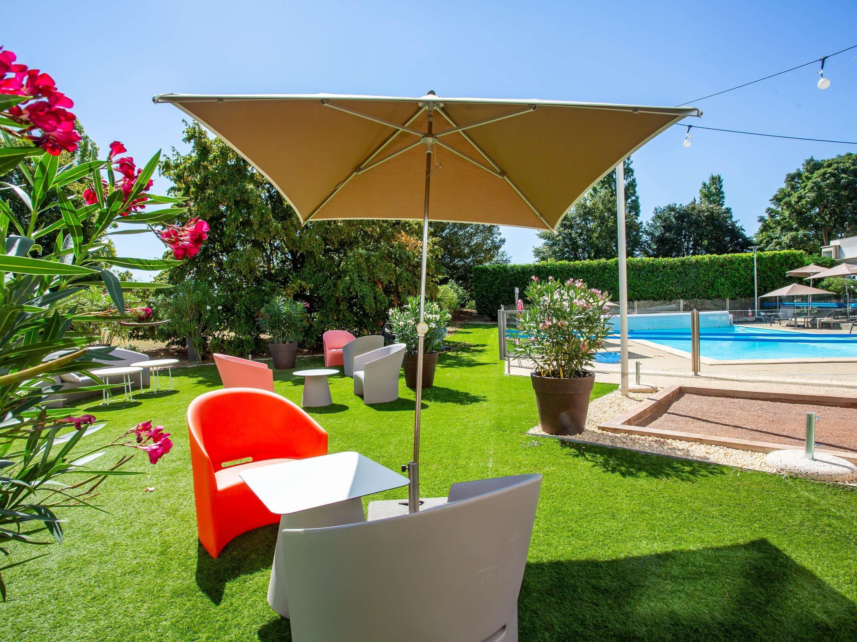 A poolside area with a pool, outdoor furniture, and a well-maintained lawn.