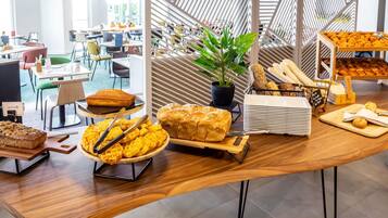 Una mesa de buffet con diferentes productos de panadería y una planta en maceta.