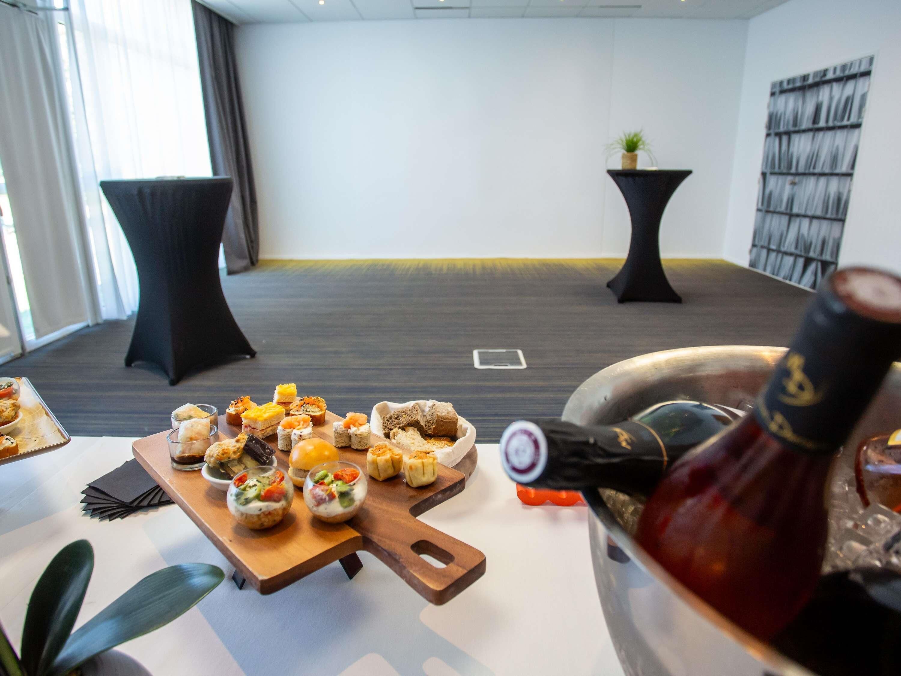 Una habitación con una mesa de comedor dispuesta con diversos bocadillos y una botella de vino.
