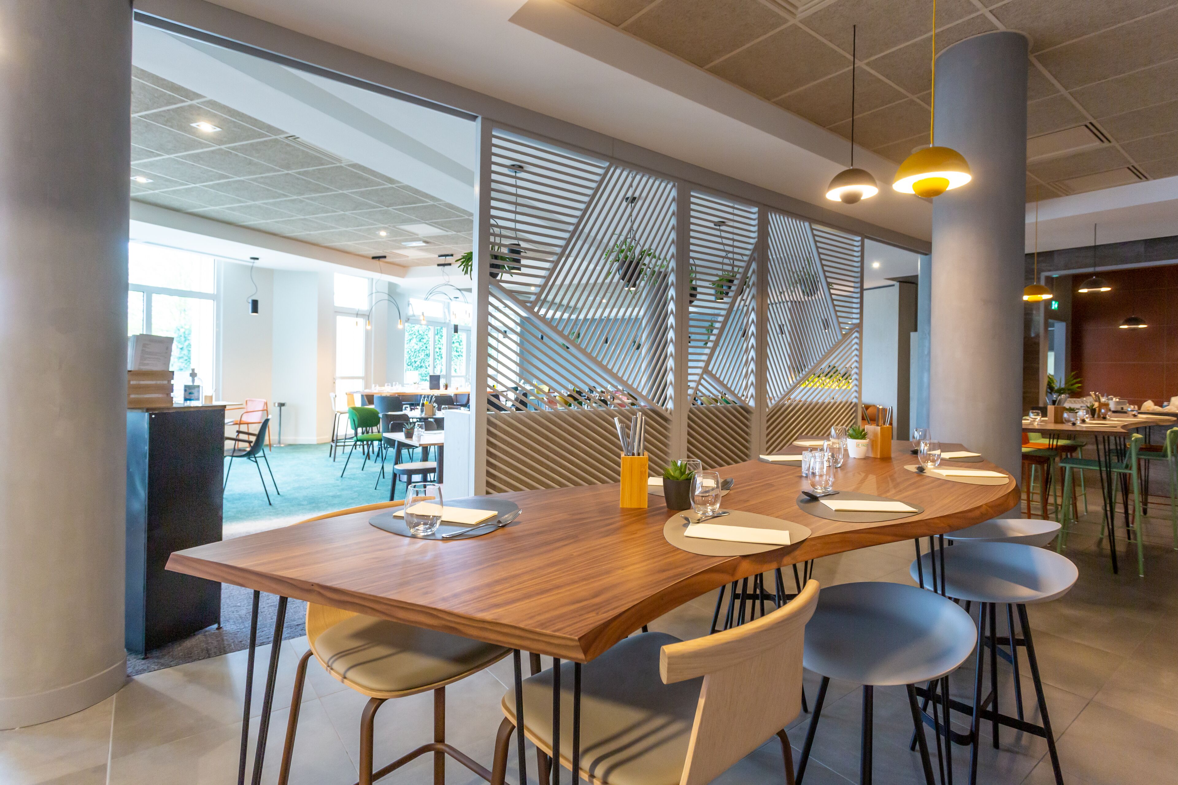 A modern dining area with a large wooden table, multiple chairs, and pendant lighting.