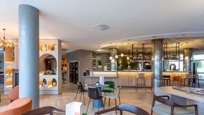 A modern bar area with seating, a counter, and shelves with bottles.