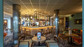 Zona de bar moderna con mostrador, asientos y una planta decorativa.