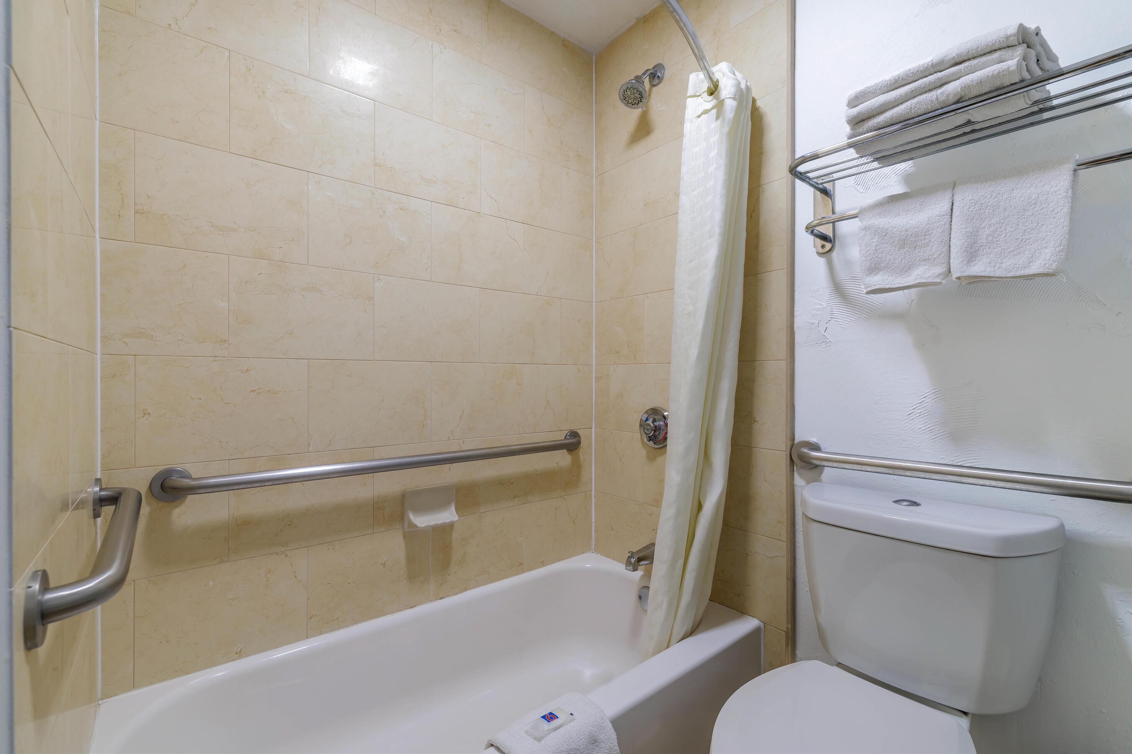 A bathroom with a bathtub, a toilet, and a shower area.