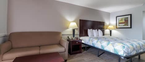 Una habitación de hotel con una cama, un sofá, una mesita y dos lámparas de noche.