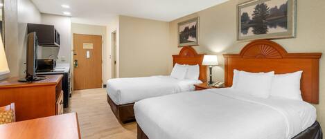 Ein Hotelzimmer mit zwei Betten, einem Schreibtisch, einem Fernseher und einem Gemälde an der Wand.