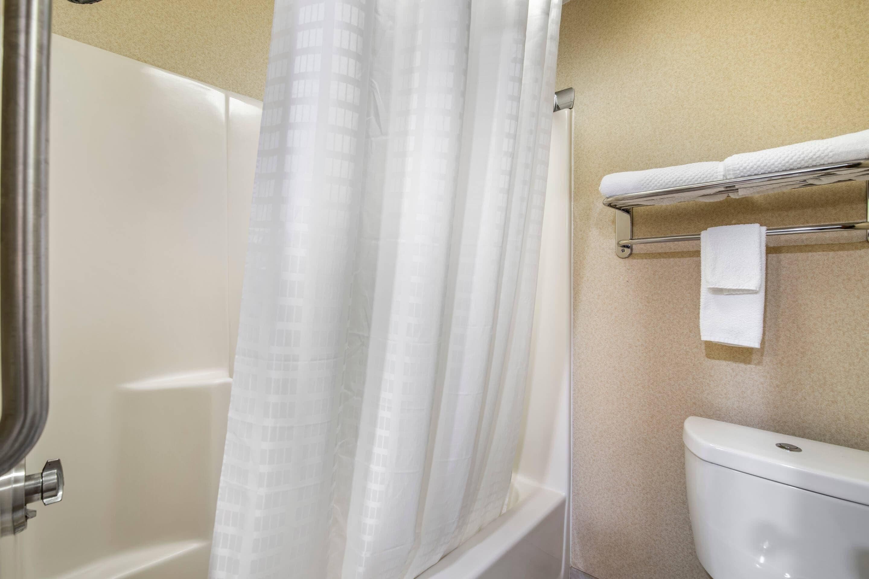 A bathroom with a bathtub, a toilet, and a towel rack with towels.
